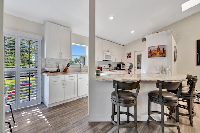 kitchen featuring white cabinets, white appliances, and kitchen peninsula