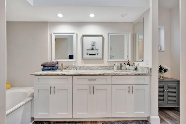 bathroom with a bathing tub, vanity, and wood-type flooring