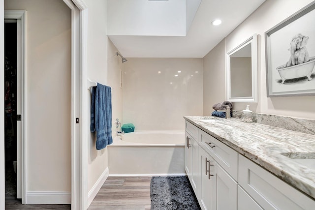 bathroom with a tub to relax in, a skylight, vanity, and hardwood / wood-style flooring