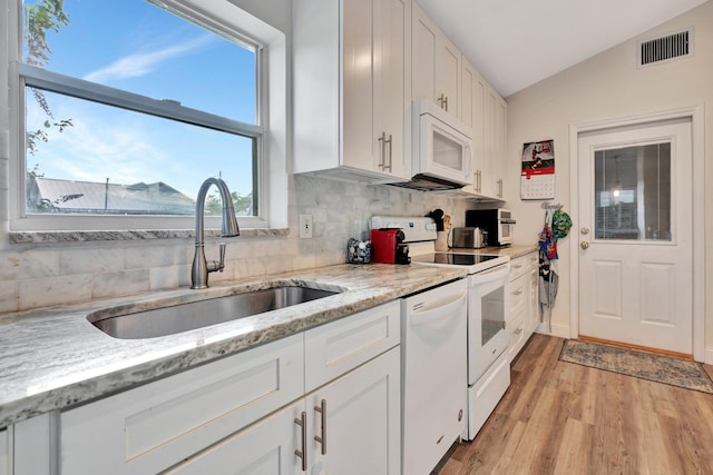 kitchen featuring lofted ceiling, white appliances, white cabinets, sink, and light hardwood / wood-style flooring