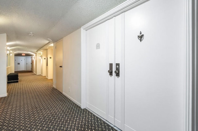 corridor with carpet flooring and a textured ceiling