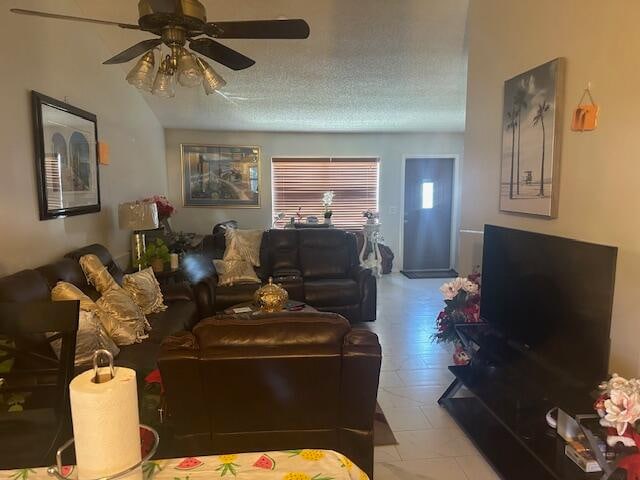 living room with ceiling fan, light tile patterned floors, and a textured ceiling