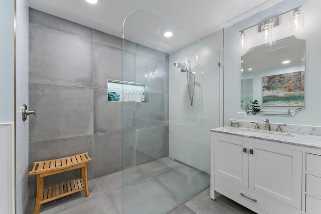 bathroom featuring a tile shower, tile patterned flooring, and vanity