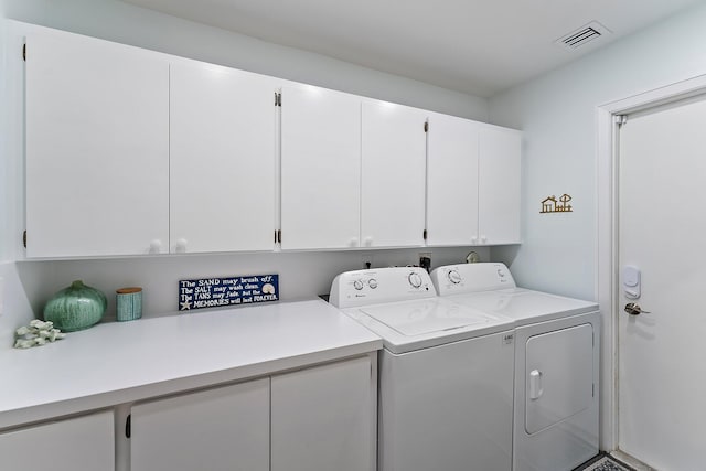 laundry room featuring washing machine and clothes dryer and cabinets