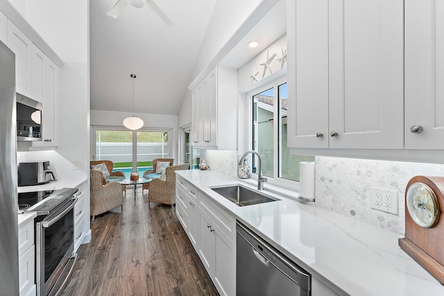 kitchen featuring dark hardwood / wood-style flooring, stainless steel appliances, vaulted ceiling, sink, and white cabinetry