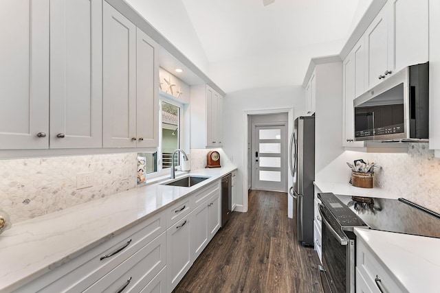 kitchen with dark hardwood / wood-style flooring, backsplash, stainless steel appliances, vaulted ceiling, and white cabinetry