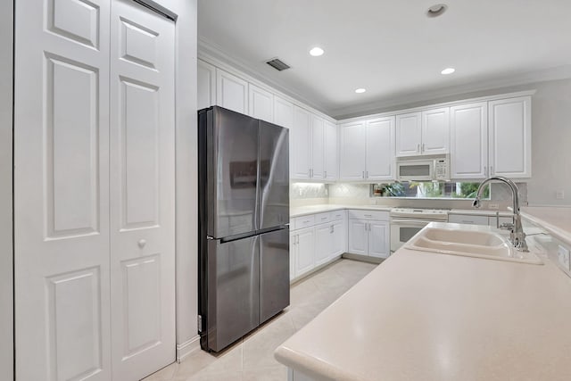 kitchen featuring white cabinetry, sink, light tile patterned flooring, and white appliances