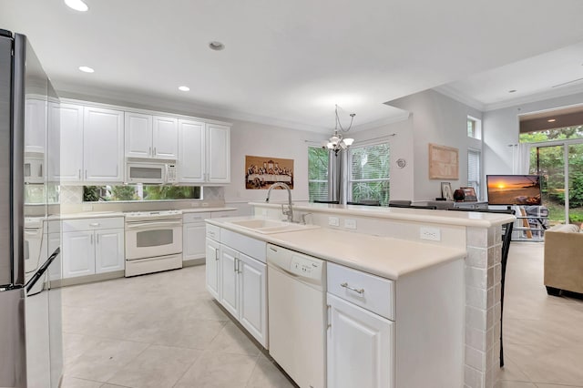 kitchen featuring sink, a notable chandelier, white appliances, a center island with sink, and white cabinets