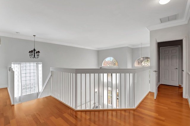 hallway featuring crown molding, light hardwood / wood-style floors, and a notable chandelier