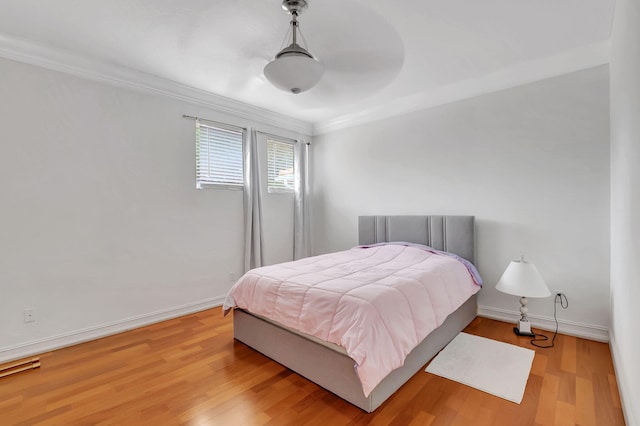 bedroom featuring ceiling fan, crown molding, and light hardwood / wood-style flooring