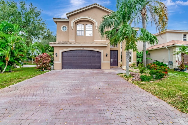 mediterranean / spanish home featuring a front yard and a garage