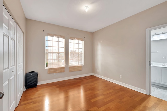 unfurnished bedroom with light hardwood / wood-style floors, ensuite bath, and a closet