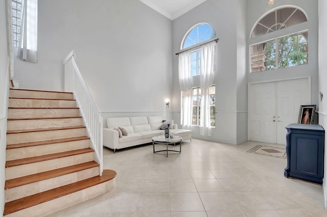 living room featuring light tile patterned floors, a high ceiling, and ornamental molding