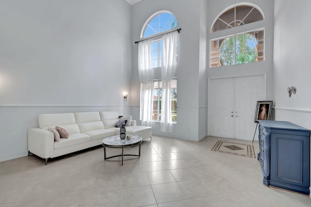 living room featuring a wealth of natural light, a towering ceiling, and light tile patterned floors