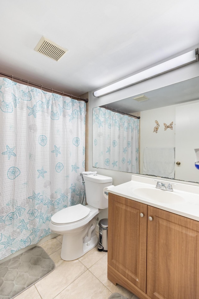 bathroom with toilet, vanity, and tile patterned floors