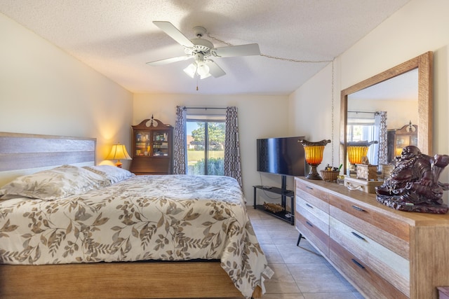 tiled bedroom with ceiling fan and a textured ceiling