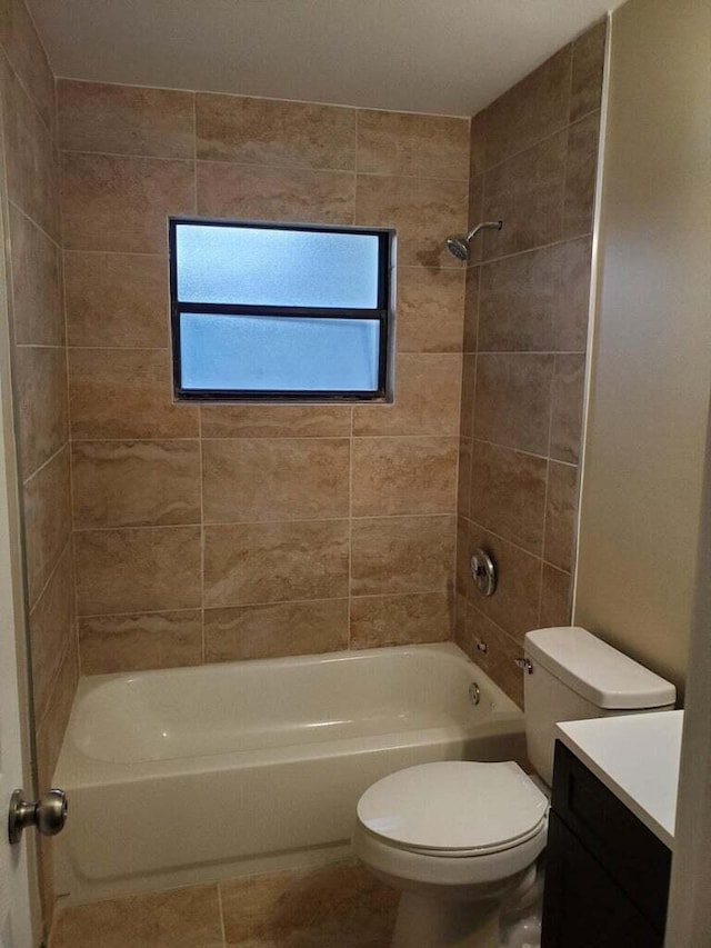 full bathroom featuring tiled shower / bath, vanity, and toilet