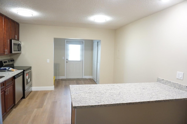 kitchen featuring light hardwood / wood-style flooring, stainless steel appliances, and a textured ceiling