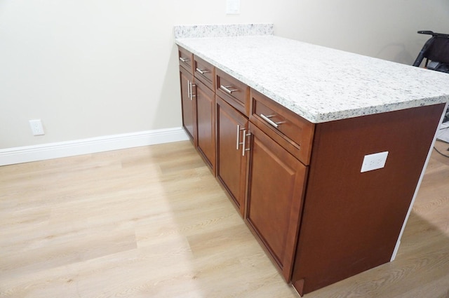 kitchen with light hardwood / wood-style floors and light stone countertops