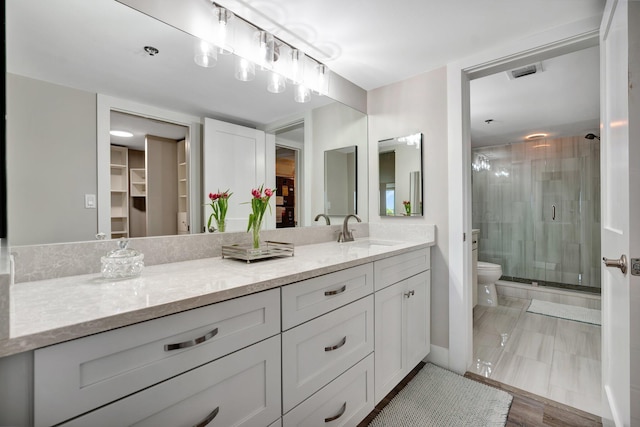 bathroom with toilet, hardwood / wood-style floors, walk in shower, and vanity