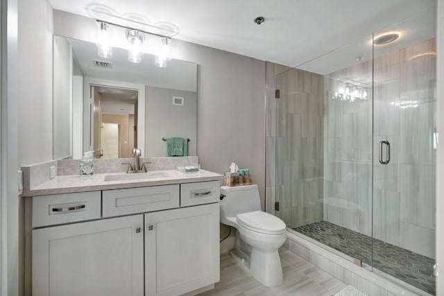 bathroom featuring toilet, vanity, and a shower with shower door