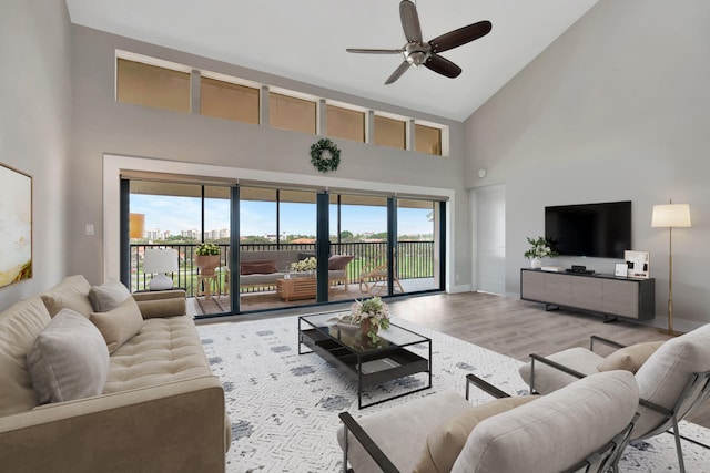 living room featuring ceiling fan, light wood-type flooring, and high vaulted ceiling