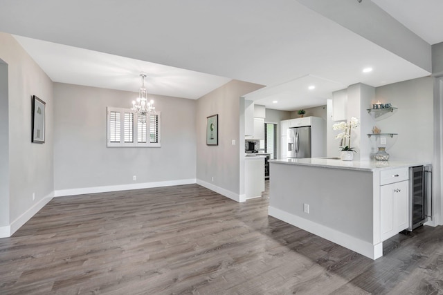 kitchen with stainless steel fridge with ice dispenser, white cabinetry, beverage cooler, and hardwood / wood-style flooring