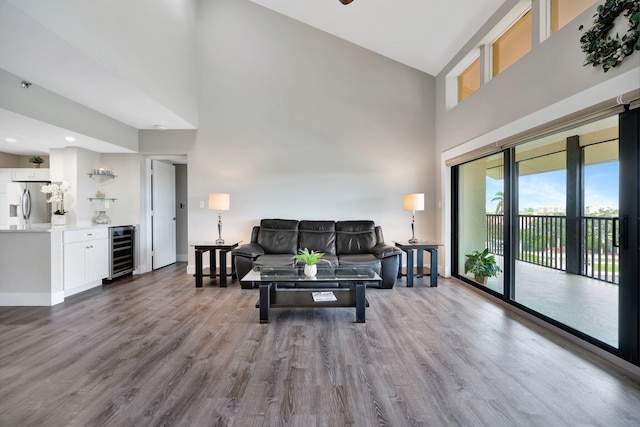 living room with wood-type flooring, a high ceiling, bar area, and wine cooler