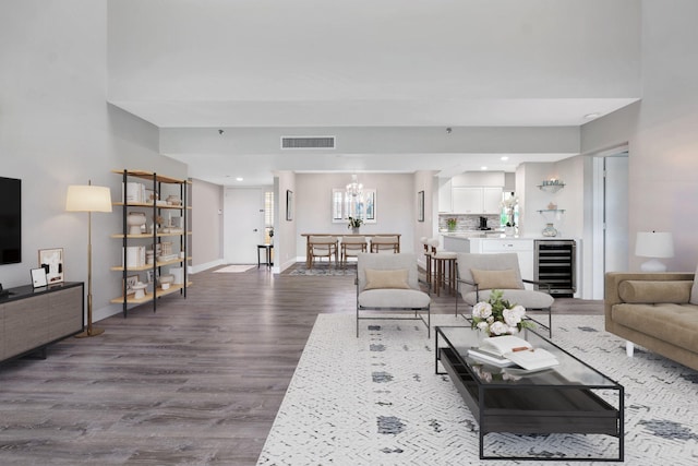 living room featuring beverage cooler, wood-type flooring, and an inviting chandelier