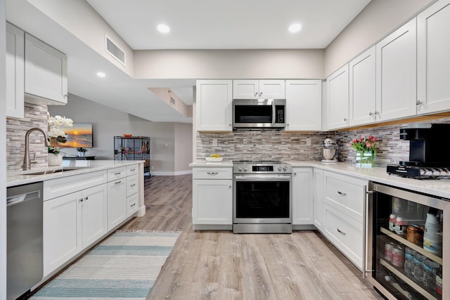 kitchen featuring white cabinets, appliances with stainless steel finishes, wine cooler, and sink