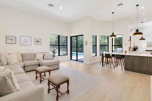 living room with a towering ceiling and light wood-type flooring