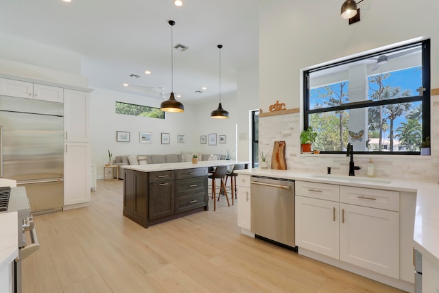 kitchen featuring pendant lighting, sink, white cabinetry, dark brown cabinetry, and premium appliances