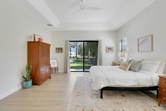 bedroom with access to exterior, light hardwood / wood-style floors, a raised ceiling, and ceiling fan