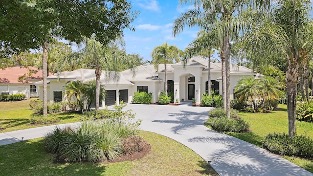 mediterranean / spanish house with a garage and a front lawn