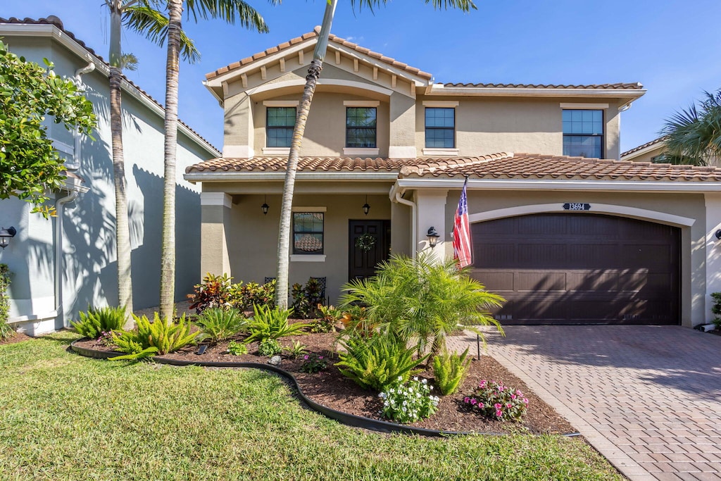 mediterranean / spanish house featuring a garage and a front lawn