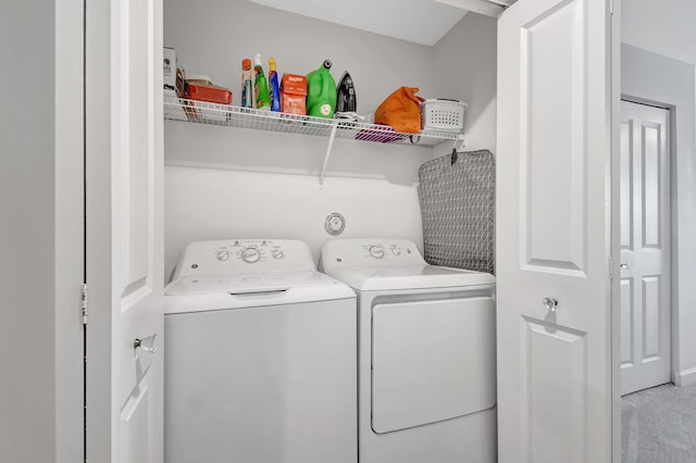 clothes washing area featuring light colored carpet and washer and dryer