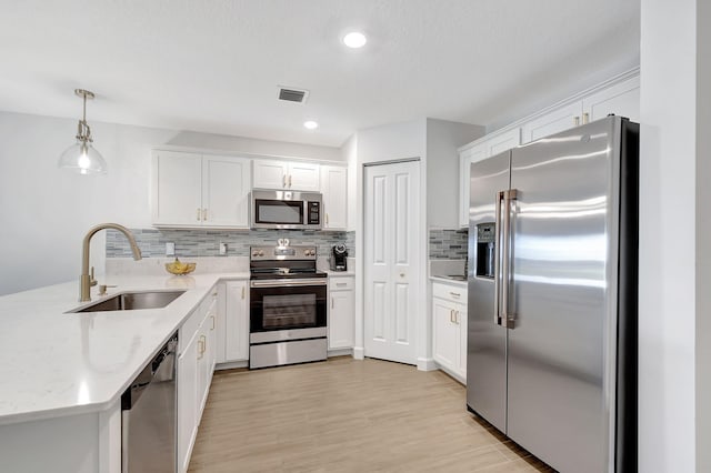 kitchen with white cabinets, stainless steel appliances, hanging light fixtures, and sink