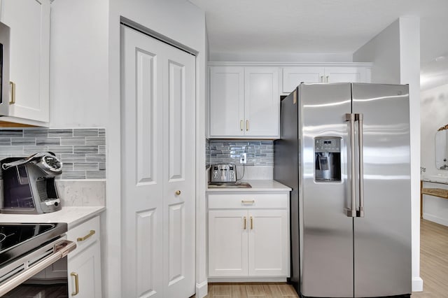 kitchen with light wood-type flooring, white cabinetry, stainless steel appliances, and tasteful backsplash