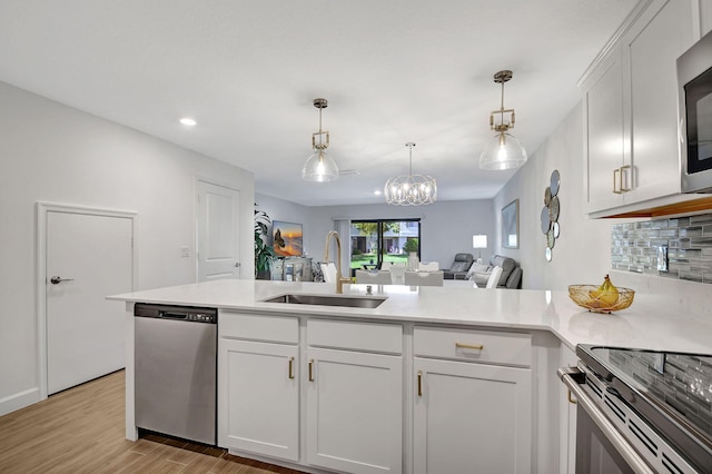 kitchen with white cabinetry, sink, light hardwood / wood-style flooring, backsplash, and appliances with stainless steel finishes