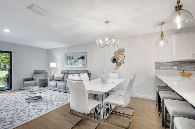 dining space with a notable chandelier and light wood-type flooring