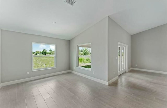 spare room with vaulted ceiling and light wood-type flooring