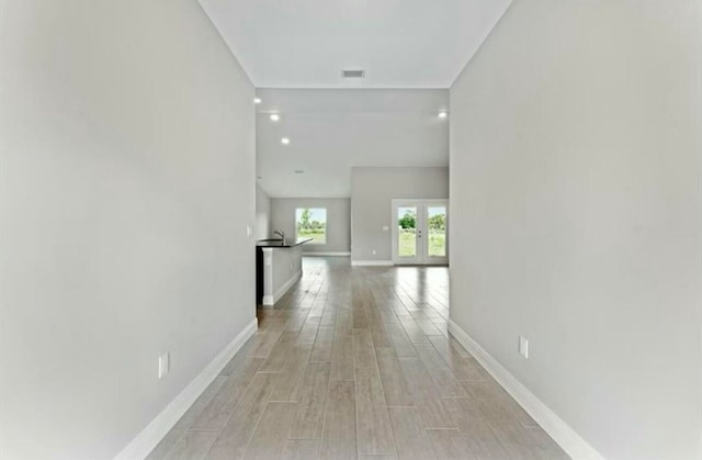 hallway with french doors and light hardwood / wood-style flooring