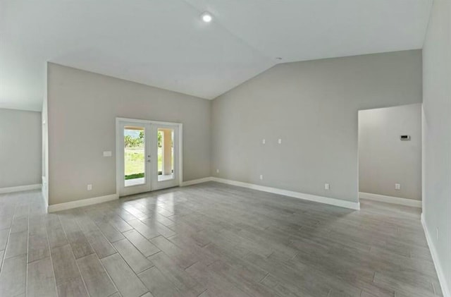 spare room featuring french doors, light wood-type flooring, and lofted ceiling