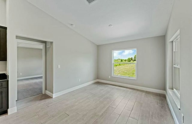 empty room with light hardwood / wood-style floors and lofted ceiling