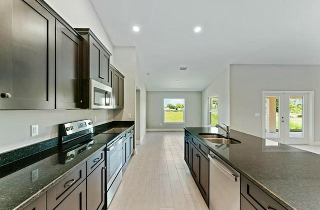 kitchen featuring stainless steel appliances, light hardwood / wood-style flooring, a wealth of natural light, and dark stone counters