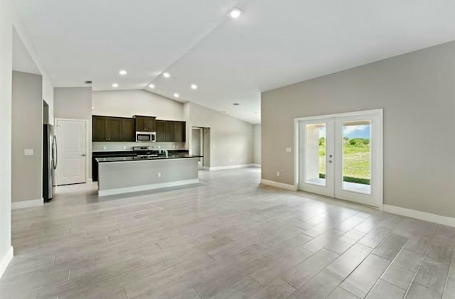 kitchen featuring a center island, light hardwood / wood-style flooring, vaulted ceiling, appliances with stainless steel finishes, and dark brown cabinetry