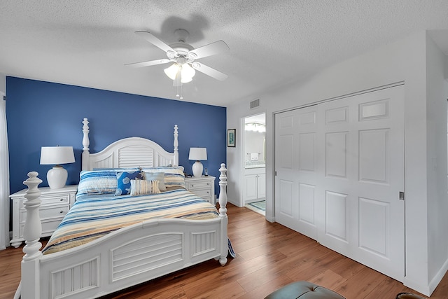 bedroom with wood-type flooring, ensuite bathroom, ceiling fan, and a textured ceiling