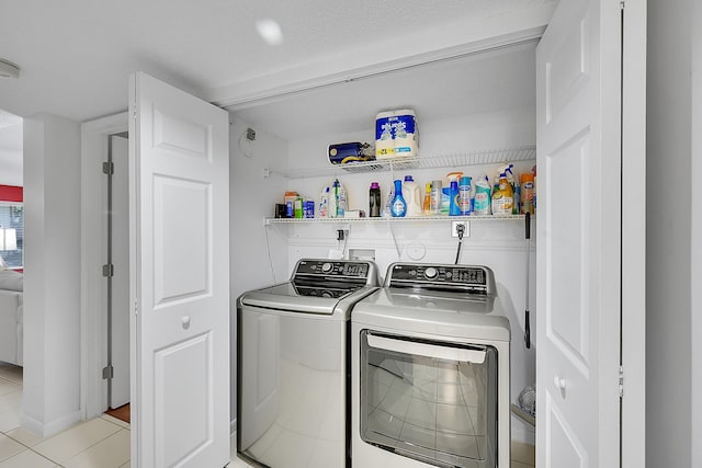 clothes washing area with light tile patterned floors and washer and clothes dryer