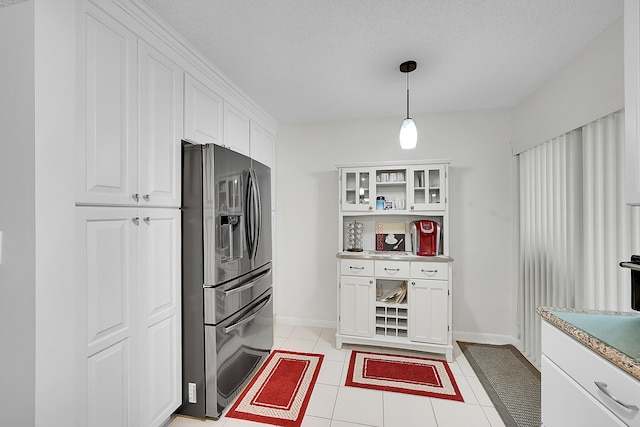 kitchen with pendant lighting, light tile patterned floors, white cabinetry, stainless steel refrigerator with ice dispenser, and a textured ceiling