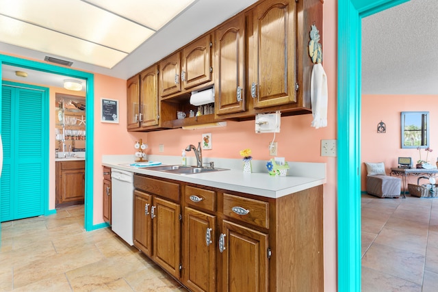 kitchen featuring sink, white dishwasher, and a textured ceiling